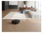 Saugroboter reinigt Holzboden in einem modernen Wohnzimmer mit Sofa und Teppich.