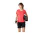 Frau in korallfarbenem Sport-T-Shirt, schwarzen Shorts und Radhandschuhen, hält einen Helm.