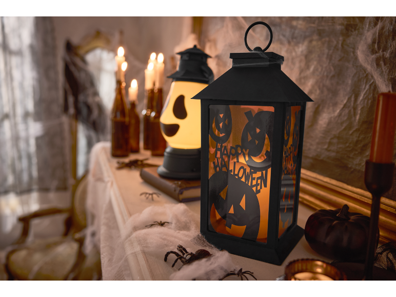 Halloween-Laterne mit „Happy Halloween“-Text, Kerzen und gruseligen Dekorationen.