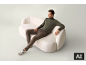 Mann sitzt auf einem weißen Sofa mit grünem Rollkragenpullover und brauner Hose.