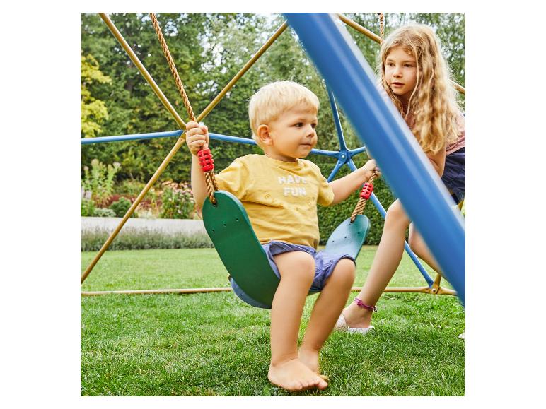 Zwei Kinder spielen auf einer Schaukel im Garten, eines auf der Schaukel.