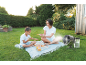 Mutter und Kind genießen ein Picknick mit einem tragbaren Ventilator im Garten.
