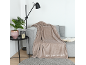 Gemütliches Wohnzimmer mit grauem Sofa, beiger Decke und Stehlampe.