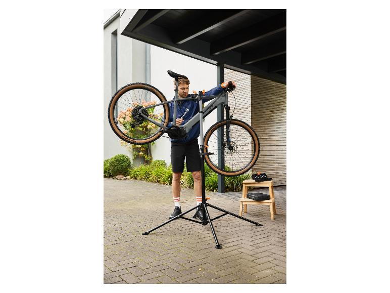 Mann repariert ein Fahrrad auf einem Fahrradreparaturständer im Freien.