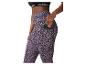 Frau in Sport-BH und Leggings mit Leopardenmuster, Handy in Seitentasche.