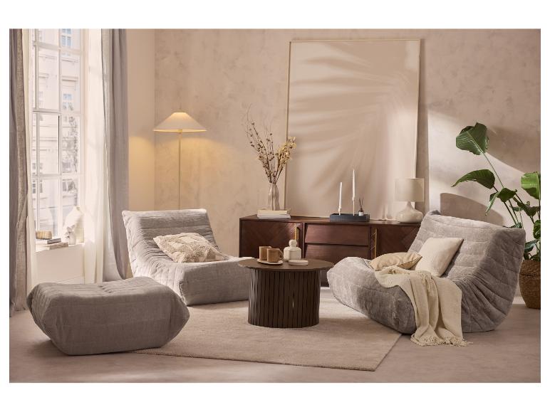 Wohnzimmer mit zwei grauen Sesseln, einem Hocker, einem Couchtisch und einem Sideboard mit Dekorationen.