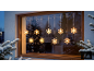 Beleuchtete Schneeflockenlichter hängen an einem Fenster in einer Winternacht.