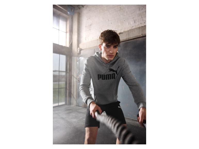 Mann trainiert mit Battle Ropes, trägt Puma Hoodie.