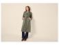 Frau in grünem Trenchcoat, Jeans und braunen Slippern.