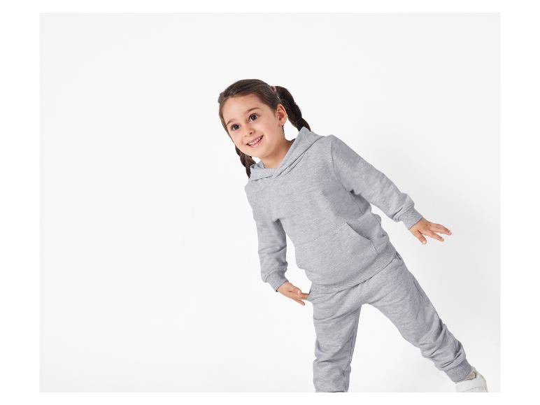 Ein junges Mädchen trägt einen grauen Hoodie und Jogginghose.