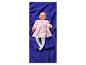 Glückliches Baby in rosa Kleid mit Herzen und weißen Strumpfhosen auf einer blauen Decke.