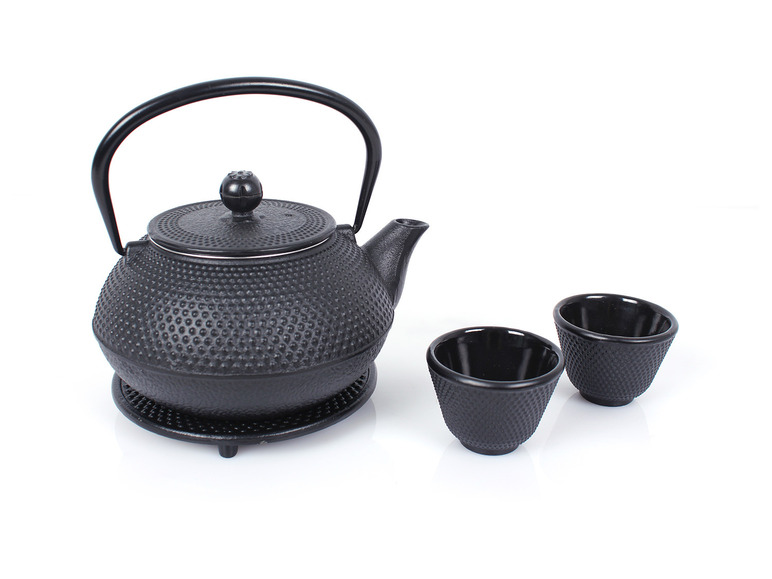 Eine schwarze Gusseisen-Teekanne und zwei Tassen.