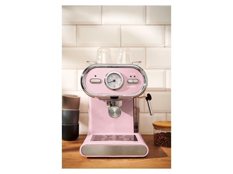 Rosa Espressomaschine mit Tassen und Kaffeebohnen auf einer Holztheke.