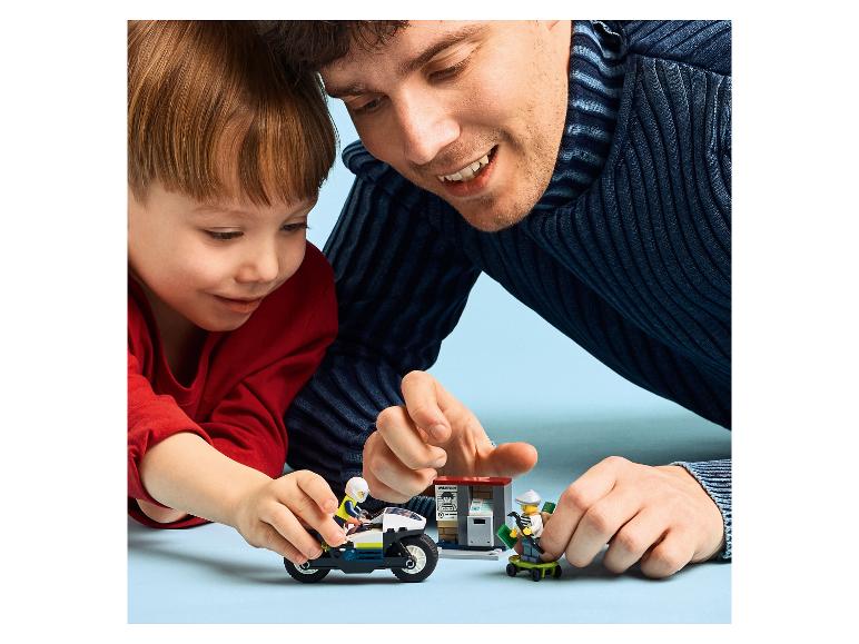 Vater und Sohn spielen mit LEGO City Polizeimotorrad und Räuberfiguren.