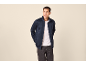 Mann in marineblauer Reißverschlussjacke und weißem T-Shirt.