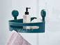 Ein grünes Eckregal mit Saugnäpfen in einer Dusche, mit Shampoo, einem Schwamm und einem Handtuch.