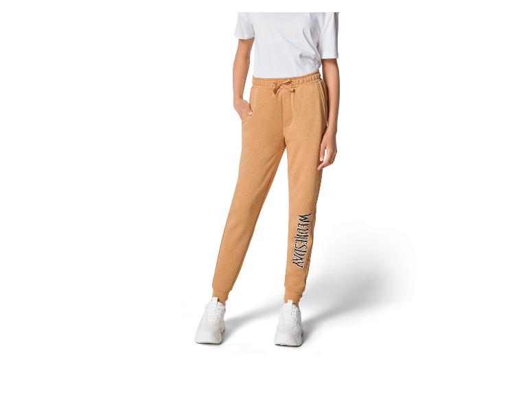 Beige Jogginghose mit 'Wednesday'-Logo und weißen Sneakern.