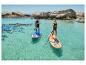 Zwei Personen auf Stand-Up-Paddle-Boards in türkisfarbenem Wasser mit Felsen im Hintergrund.