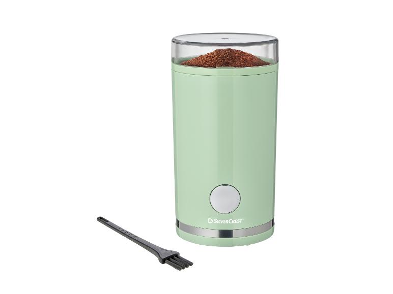 Minzgrüne elektrische Kaffeemühle mit gemahlenem Kaffee und Reinigungsbürste
