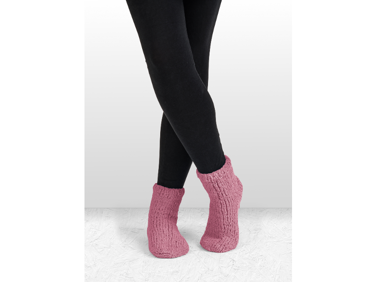 Beine in schwarzen Leggings und rosa gestrickten Hausschuhsocken.