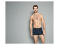 Mann in dunkelblauen Boxershorts mit Vogelmuster.