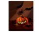 Leuchtender Halloween-Kürbis mit Dekoration auf Holzoberfläche.