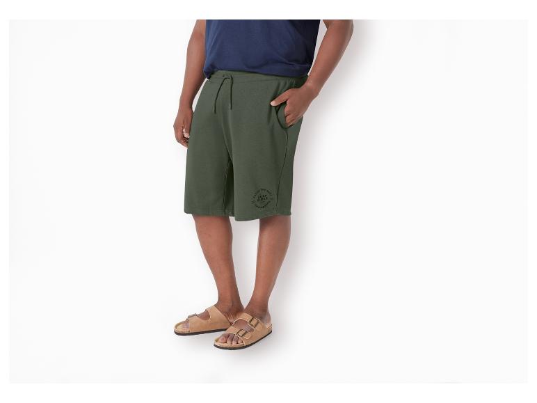Shorts und Sandalen: Ein Mann trägt olivgrüne Shorts mit einem "Surf Rider"-Logo und Sandalen.