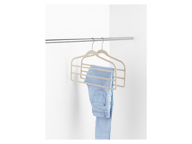 Zwei beigefarbene Samt-Kleiderbügel mit einer blauen Jeanshose