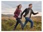 Mann und Frau in Naturlandschaft, tragen Steppjacken und Jeans.