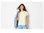Frau in besticktem T-Shirt, blauer Hose und Jeansjacke auf der Schulter.