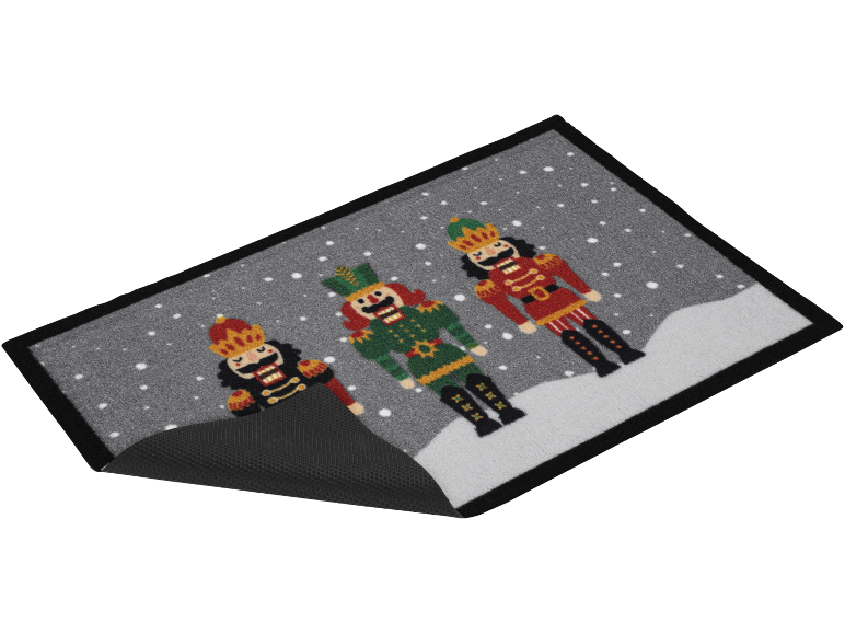 Weihnachtsmatte mit drei Nussknackerfiguren in einer Schneelandschaft.