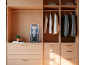 Dampfglätter in einem Holzschrank mit Kleidung und Schubladen.