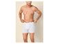 Oberkörperfreier Mann in weißen Boxershorts, der den Bund anpasst.