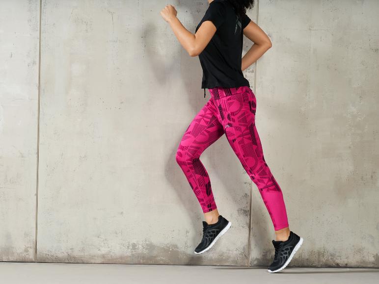 Eine Frau trägt rosa Leggings und schwarze Sneaker.