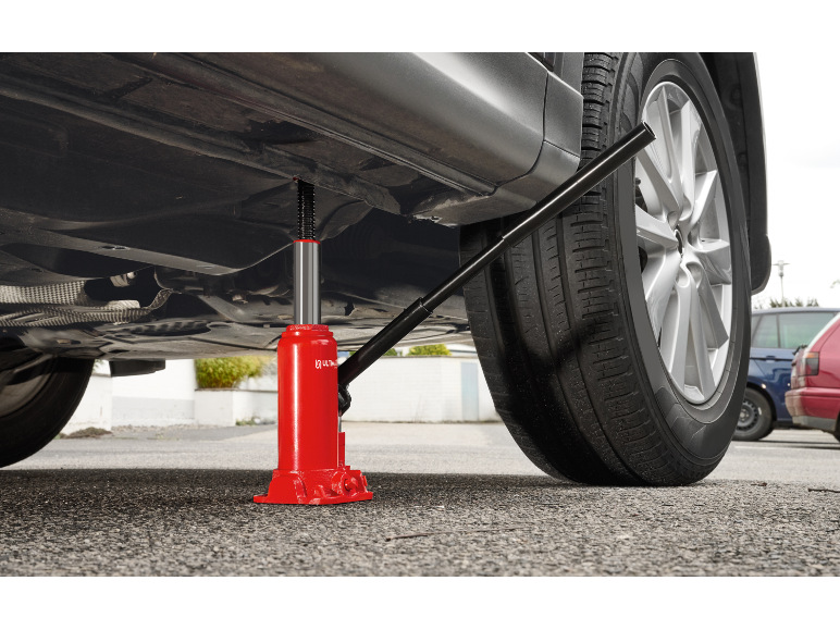 Roter Wagenheber hebt ein Auto zum Reifenwechsel an.