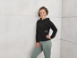 Eine Frau in einem schwarzen Hoodie und grünen Leggings.