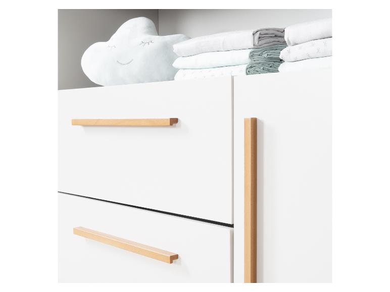 Weiße Kommode mit Holzgriffen und einem wolkenförmigen Kissen mit Bettwäsche.