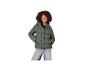 Frau in grüner Steppjacke und Jeans, mit Händen in den Taschen.