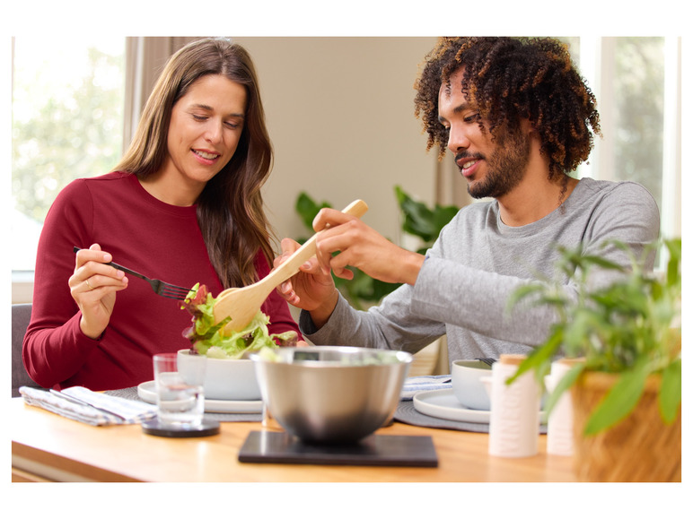 Ein Paar genießt einen Salat mit einer Holzschaufel und Besteck.
