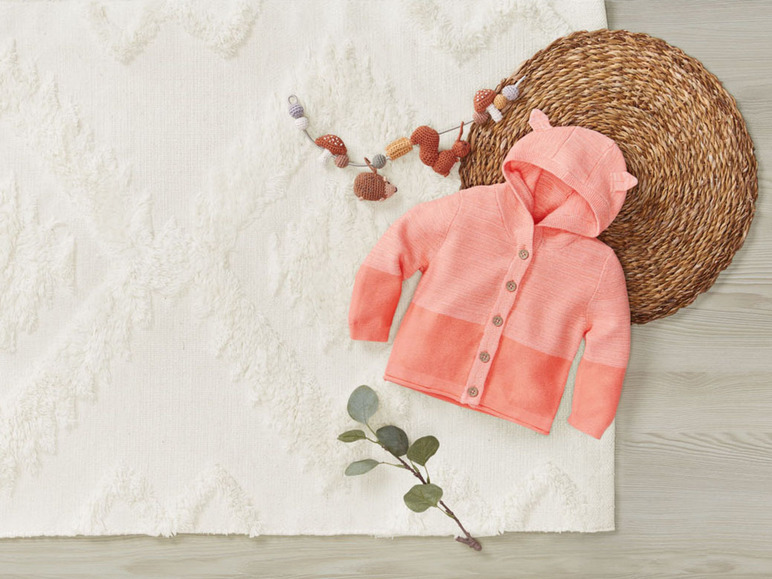 Ein rosafarbenes Strickjäckchen mit Kapuze für Babys.