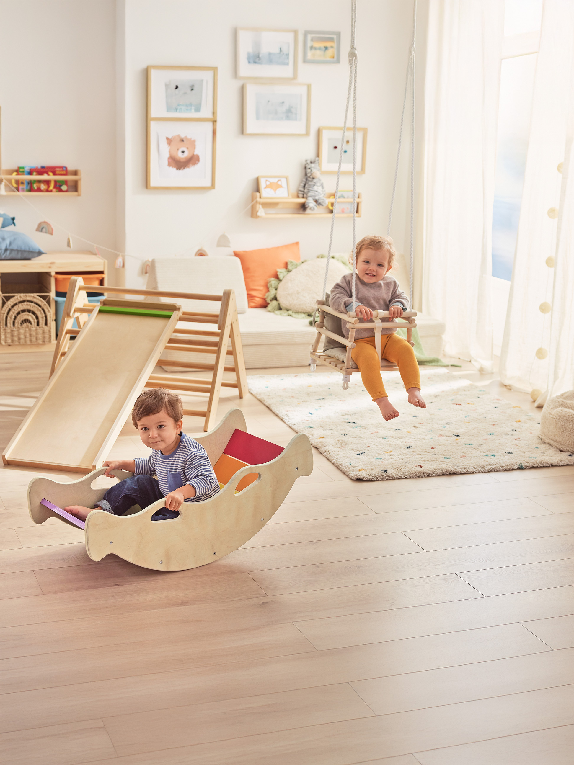 Zwei glückliche Kleinkinder spielen mit Holzspielzeug in einem hellen Kinderzimmer.