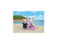 Zwei Hasenfiguren, eine im Matrosenanzug und eine im lila Kleid, am Sandstrand.
