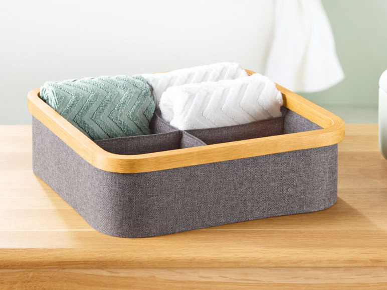 Eine graue Aufbewahrungsbox mit Holzrand, gefüllt mit Handtüchern.