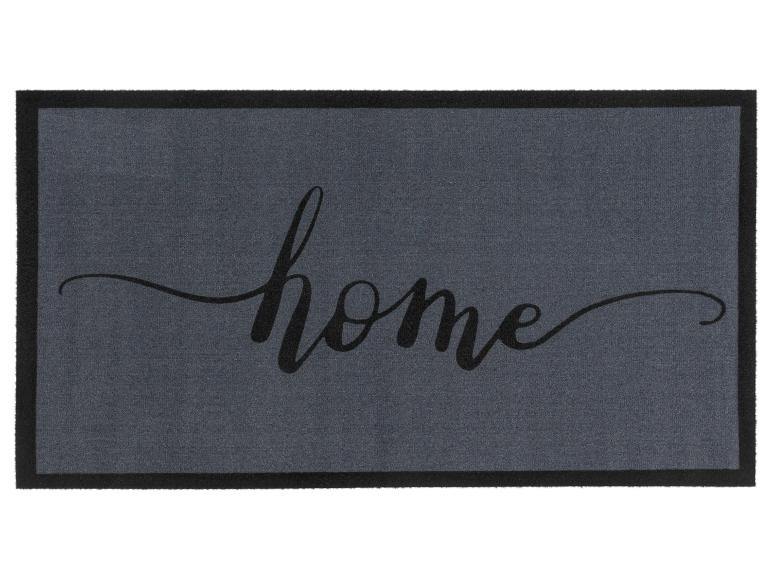Eine graue Fußmatte mit schwarzem Rand und dem Schriftzug 'home' in Kalligraphie.
