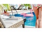 Ein weißer Lautsprecher auf einem Liegestuhl am Pool mit einem aufblasbaren Flamingo.