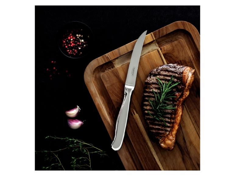 Steak mit Rosmarin auf Holzschneidebrett, mit Messer, Knoblauch und Pfeffer.