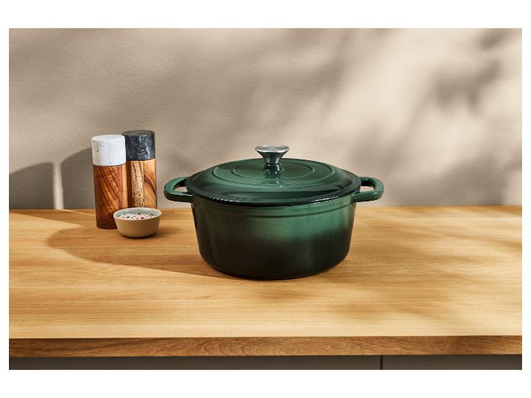 Grüner gusseiserner Topf auf einer Holztheke.