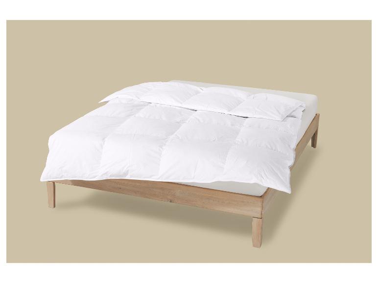 Holzbett mit weißer Bettdecke und Kissen.