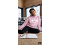 Mädchen in rosa Kapuzenpullover und schwarzen Leggings, auf dem Boden sitzend.