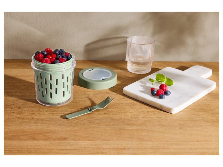Snackbehälter mit Heidelbeeren, Himbeeren und Johannisbeeren, daneben eine Klappgabel und ein Brett mit Früchten.